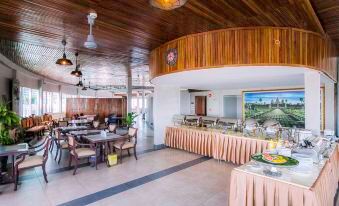 a dining area with multiple tables and chairs , as well as a buffet table filled with food at Paradise Hotel