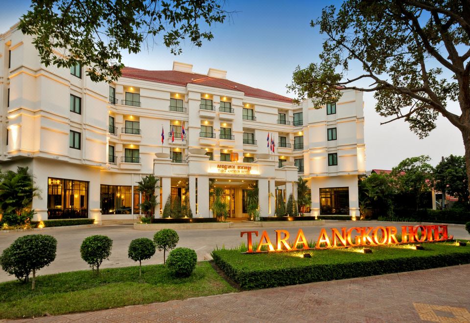 the tara angkor hotel is a large white building with trees and shrubs in front at Tara Angkor Hotel