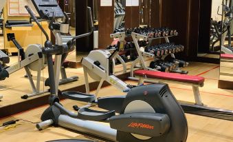 a gym with various exercise equipment , including a treadmill , an elliptical machine , and a stationary bike at Sheraton Qinhuangdao Beidaihe Hotel