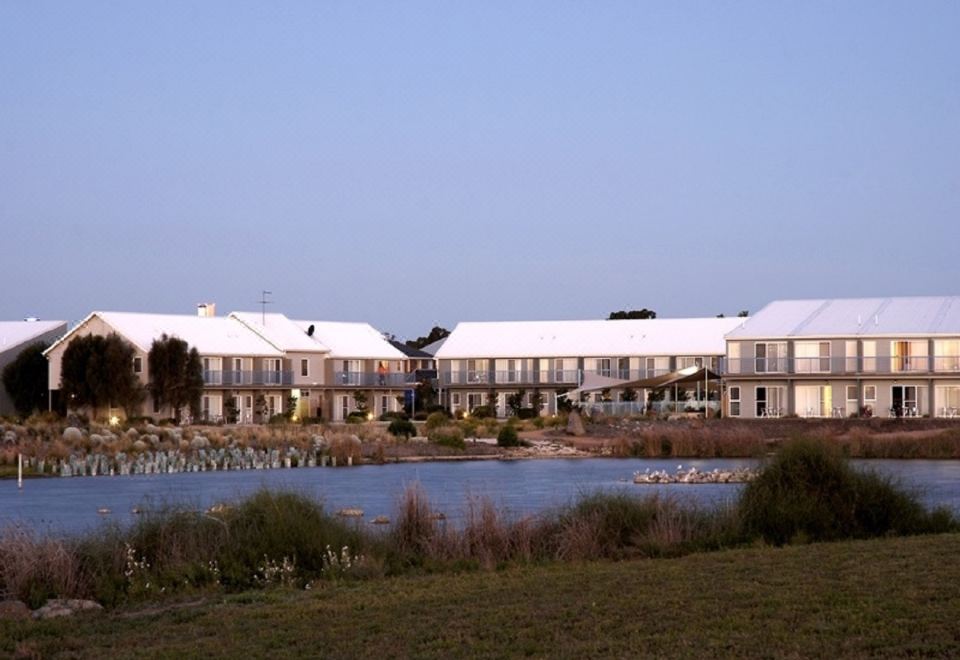 a large , modern building with a distinctive architectural design is situated on the edge of a body of water at Quest Williamstown North