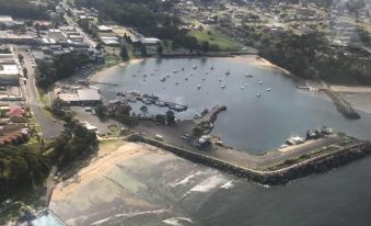 a bird 's eye view of a coastal area with boats docked , buildings , and a small town at Ulladulla Motel