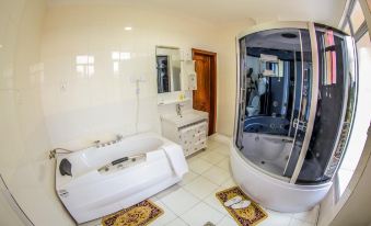 a white bathroom with a bathtub and a shower , as well as a toilet and sink at Fatima Hotel