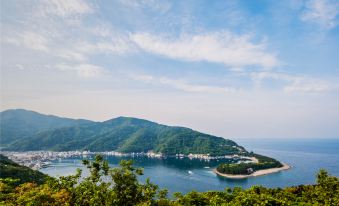 The view from the top showcases a scenic landscape with water, mountains, and boats docked in the background at Nishi-izu Resort Kumo To Kaze To／Tenkuu-Terrace