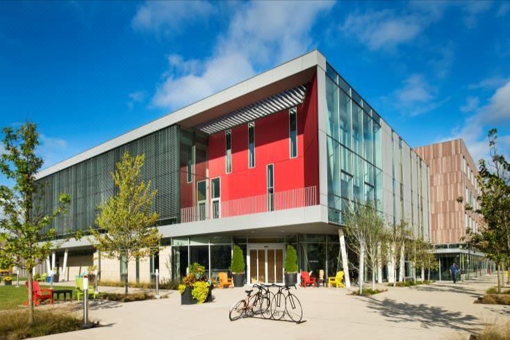 a modern building with a red facade and large windows , surrounded by trees and bicycles parked outside at The Hotel at Oberlin