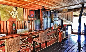a wooden bar with a thatched roof , surrounded by potted plants and other decorations , creating a warm and inviting atmosphere at Taatoh Seaview Resort