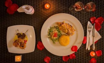 a table is set with two plates of food , one containing meat and rice , and the other with a side salad at Riviera Del Sol Hotel Spa