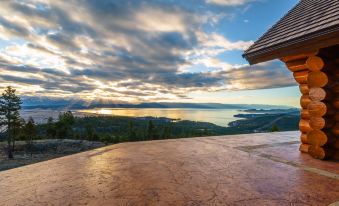 a wooden house with a tiled roof is perched on a cliff overlooking a lake at Coyote Bluff Estate