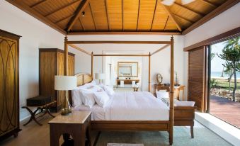 a spacious bedroom with a four - poster bed in the center , surrounded by various pieces of furniture at The Residence Zanzibar