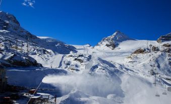 a snowy mountain landscape with a ski lift and snow - covered slope , under a clear blue sky at Hotel Petit Palais