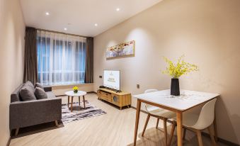 An apartment with a spacious living room featuring large windows, a television, and a central table at Livefortuna Hotel