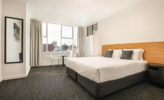 a large , well - lit bedroom with a bed , desk , and chair , along with a window and balcony at Nightcap at Waltzing Matilda Hotel