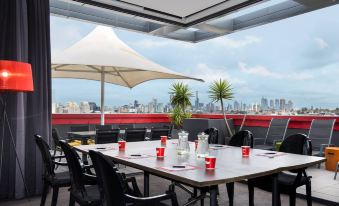 a rooftop restaurant with a table and chairs , umbrellas , and a view of the city at The Cullen Melbourne - Art Series