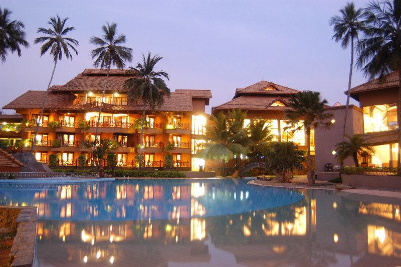 a large hotel with multiple buildings and palm trees surrounding a swimming pool at dusk at Royal Palms Beach Hotel