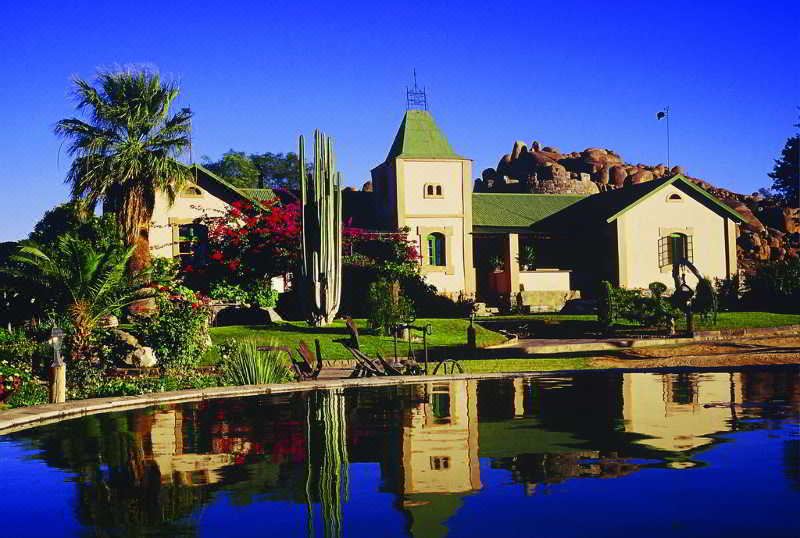 a serene scene with a large house surrounded by a garden , with a pond in the foreground at Canyon Lodge