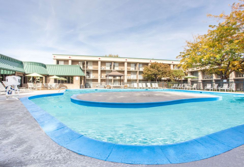 an outdoor swimming pool surrounded by a hotel building , with people enjoying their time in the pool at Gateway Hotel