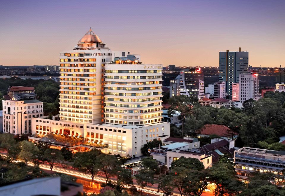 At night, there is a view of an illuminated skyscraper and other buildings in the city at Sofitel Saigon Plaza