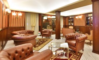 a spacious living room with brown leather couches , chairs , and tables arranged in an open space at Phi Hotel Principe