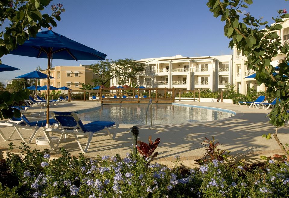 a large outdoor swimming pool surrounded by lounge chairs and umbrellas , creating a relaxing atmosphere at Beach View Hotel