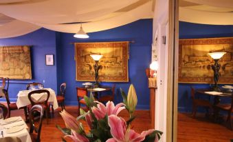 a dining room with blue walls , wooden floors , and various furniture pieces including chairs , tables , and paintings at Seaview House