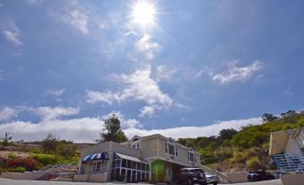 a house with a garage is surrounded by trees and parked cars under a sunny sky at Malibu Country Inn