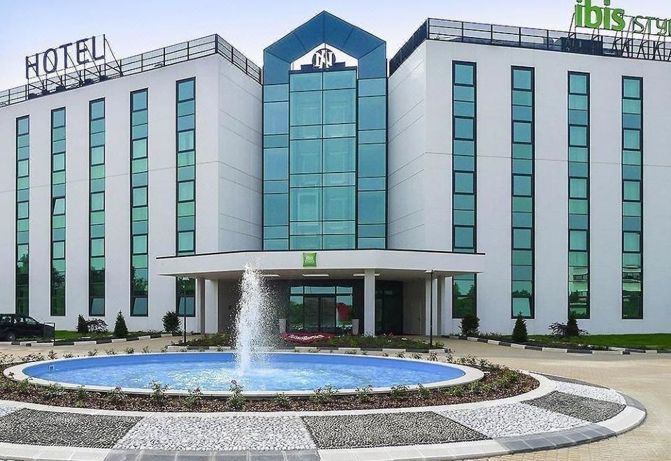 a large building with a fountain in front of it , located on a city street at Ibis Styles Milano Est Settala