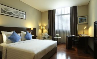 a large bed with blue pillows is in a room with wooden floors and a window at Novotel Jakarta Mangga Dua Square