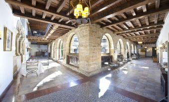an old stone building with a high ceiling , where several chairs and tables are set up for dining at Parador de Cangas de Onis