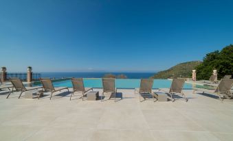 a group of chairs and a table are arranged on a patio overlooking the ocean at Best Western Plus Hotel Terre di Eolo