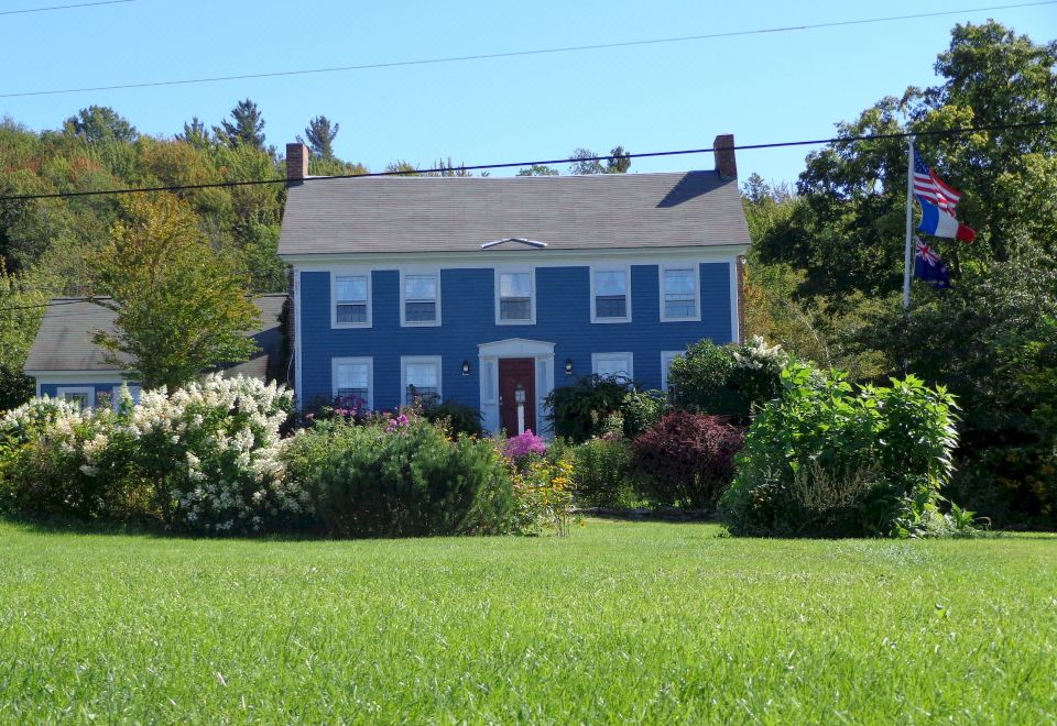 a blue house with white trim , surrounded by a lush green lawn and a garden at Blueberry Hill Inn