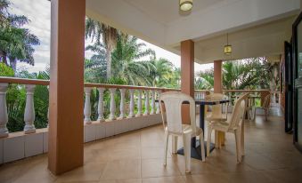 a balcony with a table and chairs , surrounded by palm trees and overlooking a body of water at Hibis Hotel