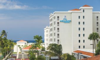 "a large hotel with a blue sign that says "" aruba sun "" is surrounded by palm trees and ocean" at Aquarius Vacation Club at Dorado del Mar
