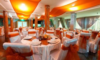 a large banquet hall with round tables covered in white tablecloths and chairs arranged for a formal event at Hotel Perla