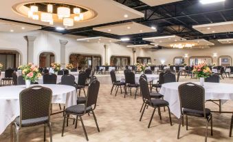a large banquet hall filled with round tables and chairs , ready for a formal event at Quality Inn Festus