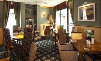 a dining room with wooden tables and chairs arranged for a group of people to enjoy a meal together at Premier Inn Herne Bay