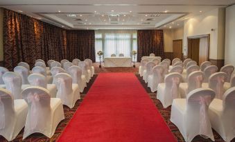 a large conference room with rows of chairs and a red carpet , set up for an event at Coldra Court Hotel by Celtic Manor