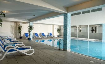 a hotel pool area with a lounge chair , lounge area , and sliding glass doors leading to the pool at Hotel Park