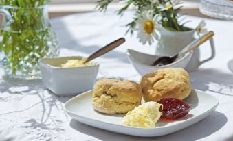 a plate of biscuits and cream on a dining table , accompanied by a spoon and a flower arrangement at Marsh House Farm