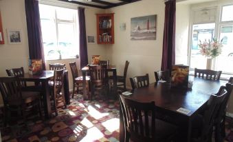 a dining room with wooden tables and chairs , purple curtains on the windows , and a window in the background at The Kings Head