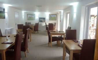 a large dining room with wooden tables and chairs arranged for a group of people to enjoy a meal together at Parrett Hotel