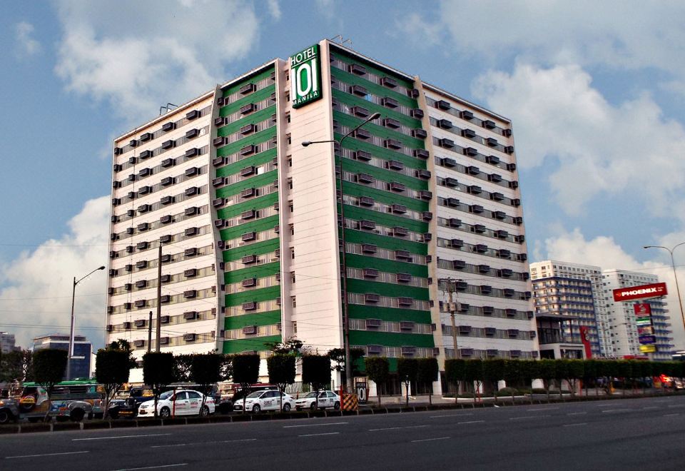 "a tall , green and white building with the brand "" o "" on top , surrounded by a parking lot and trees" at Hotel 101 Manila