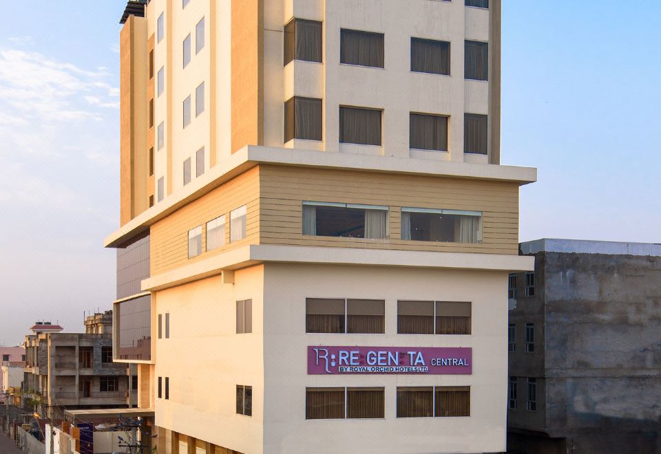 a tall building in the middle of a city street , surrounded by other buildings and trees at Regenta Central Jaipur