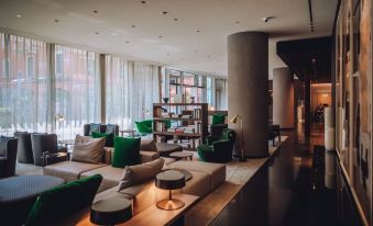 a modern living room with various seating options , including couches , chairs , and a dining table at Hotel Viu Milan, a Member of Design Hotels