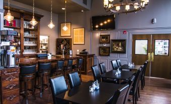 a dining room with a long wooden table surrounded by chairs , and several paintings hanging on the wall at Meadows Hotel