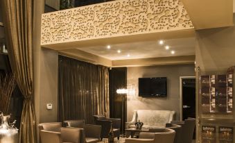 a modern living room with high ceilings , stone walls , and various pieces of furniture , including sofas , chairs , and a coffee table at Queen's Hotel - Zebra Centre