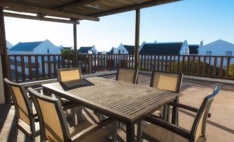 a wooden patio set with chairs and a table is shown on a deck overlooking houses at De Nada