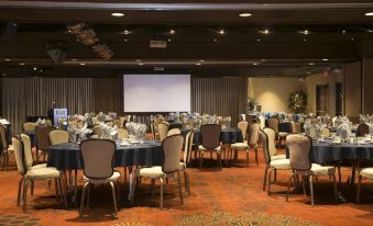 a large conference room with multiple tables and chairs , a projector screen , and well - lit carpeting at Carson Valley Inn
