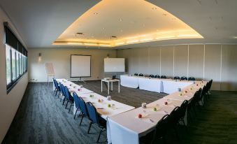 a long dining table set up for a conference , with chairs arranged around it and a whiteboard on the wall at Alpha Hotel Eastern Creek