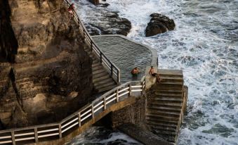 a group of people standing on a wooden staircase near the ocean , enjoying the scenic view at Acantilados