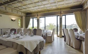 a large , elegant dining room with tables covered in white tablecloths and chairs arranged around them at Chateau le Cagnard