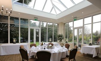 a well - arranged dining room with tables set for a formal dinner , surrounded by large windows and skylights at St Andrews Town Hotel